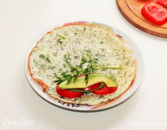 Готовые омлеты выложить на тарелки, сверху разложить нарезанное авокадо, помидоры и оставшиеся листья петрушки, посолить, поперчить.