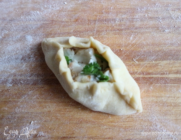 Защипнуть края, оставив серединку расстегая свободной от теста. Можно заранее приготовить небольшие «рыбки» из теста, которые обычно прикрепляют к расстегаю с рыбной начинкой. Если начинка грибная, украшение из теста — «грибок».