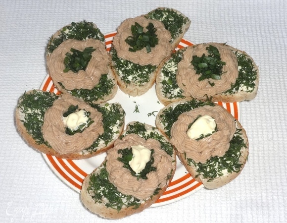 В получившееся углубление выложить немного нарезанного зеленого лука, капнуть небольшое количество майонеза и положить перепелиное яйцо. Посыпать бутерброды молотым перцем.