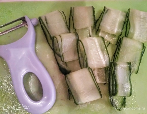 Слайсером или овощечисткой нарезать огурец тонкими слайсами.