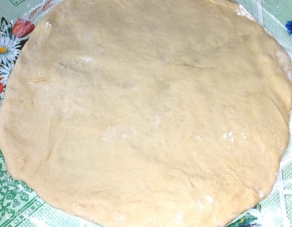 Разделить тесто на 2 неравные части: одна чуть больше другой. Стол посыпать мукой. Раскатать большую часть теста в круг, равный диаметру формы плюс бортики.