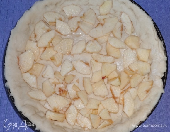 Сковороду смазать маслом. Выложить раскатанное тесто на дно и борта сковороды, лишнее тесто срезать. Положить на дно нарезанные яблоки, сбрызнуть лимонным соком.