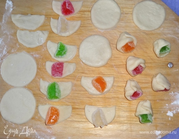 Каждый кружок теста разрезать пополам. На половинки кружков разложить кусочки мармелада. Обернуть тесто вокруг кусочка мармелада, чтобы было похоже на бутон цветка.