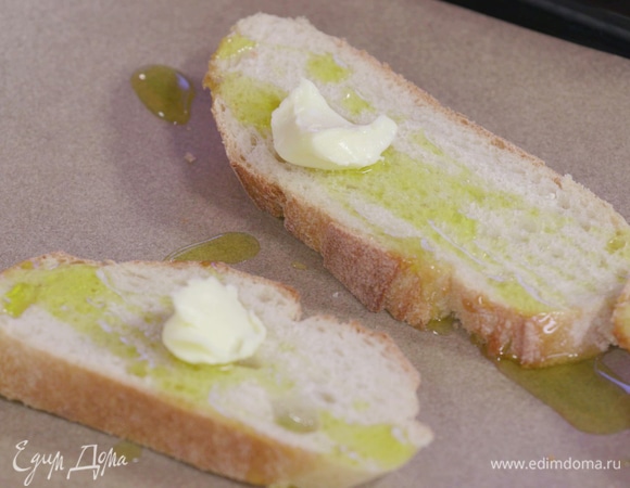 Противень накрыть бумагой для выпечки. Хлеб нарезать на 4 ломтя, выложить их на противень, каждый полить небольшим количеством оливкового масла, а сверху выложить по кусочку сливочного. Выпекать в духовке до золотистой корочки.