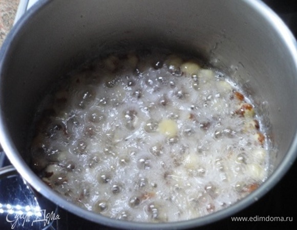 В маленькую кастрюльку наливаем 30 мл воды, всыпаем весь сахар и орехи. Варим карамель на среднем огне до пробы на тонкую нить.