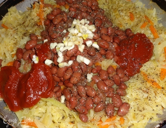 Затем добавить к капусте консервированную фасоль, измельченный чеснок, соль, сахар, перец, томатную пасту, перемешать. Потушить без крышки 5–7 минут.