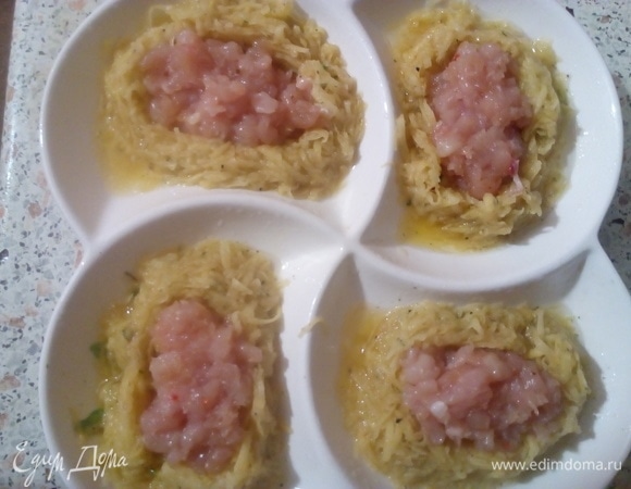 В картофельные гнезда сложить рубленую курицу. Поставить запекаться в печь. Печь 35 минут при температуре 180°C.