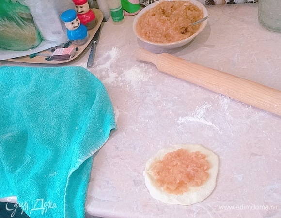 От теста взять часть и переложить на рабочий стол. Соорудить жгут, нарезать на равные части. Раскатываем пласт и кладем 1–2 ч. л. начинки (у меня часть пирожков была с яблоком, часть — с капустой).