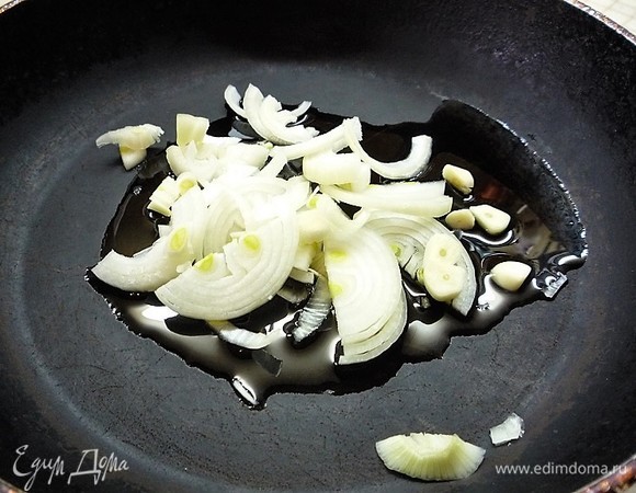 В глубокой сковороде разогреваем оливковое масло, выкладываем лук с чесноком и, помешивая, томим на медленном огне 5–7 минут.