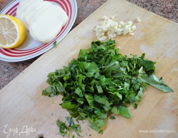 Духовку разогреть до 190°C. Зелень крупно нарезать, чеснок порубить. Моцареллу нарезать ломтиками по 4–5 мм.