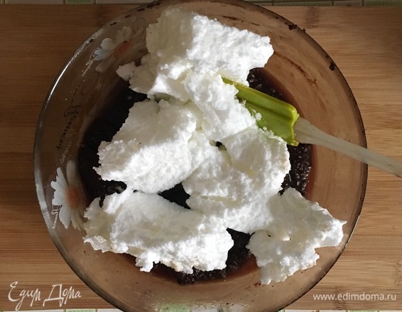 Не прекращая взбивать, ввести шоколадно-сливочную массу и всыпать измельченные орехи. Затем частями вмешать взбитые белки.