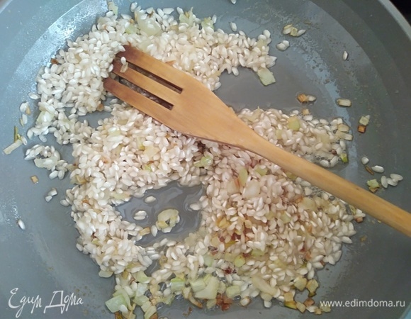 Всыпать рис для ризотто. Перемешать, чтобы рис пропитался ароматным маслом. На соседней конфорке довести до кипения бульон. Куриный можно заменить на овощной.