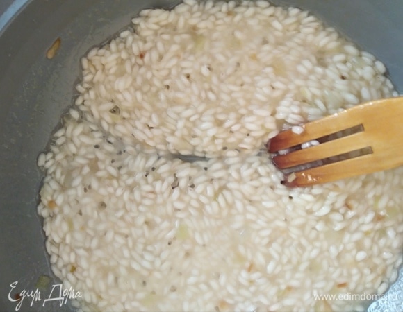 Постепенно добавлять по половнику бульон. Огонь убавить до среднего. Следить за тем, чтобы рис не плавал в жидкости, а впитывал ее. Помешивать постоянно.