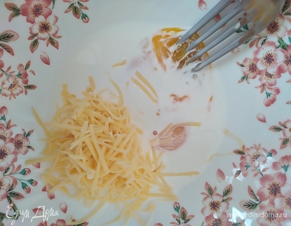 Сыр натереть на мелкой терке. Смешать в миске желток, сливки и половину тертого сыра. Добавить лимонный сок и цедру.