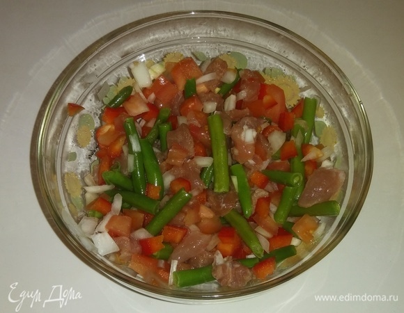 В глубокую емкость кладем нарезанные овощи, мясо и фасоль. Добавляем оливковое масло, блинную муку, соль, перец, аджику и измельченный сушеный помидор. Все перемешиваем.