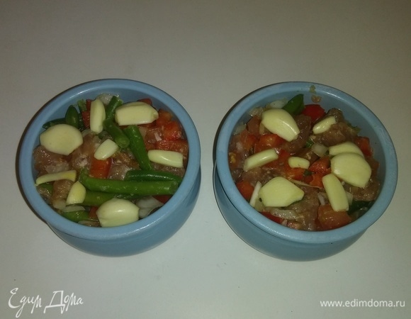 Перекладываем смесь овощей и мяса в горшочки, украшаем сверху нарезанным чесноком и ставим в разогретую до 185°C духовку на 40 минут (время приготовления зависит от духовки). Приятного аппетита!