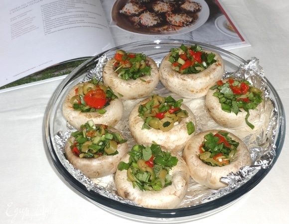 Шляпки грибов наполнить оливковой начинкой и выложить на противень.