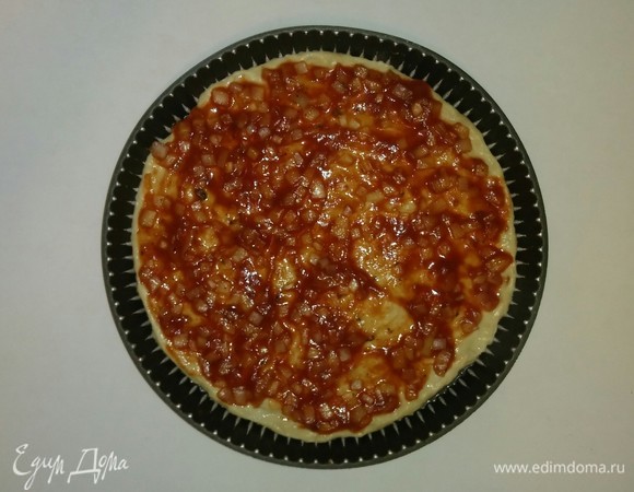 Смазываем форму для выпечки оливковым маслом, затем чуть-чуть присыпаем мукой и раскатываем тесто по форме. Смазываем тесто чуть остывшим соусом.