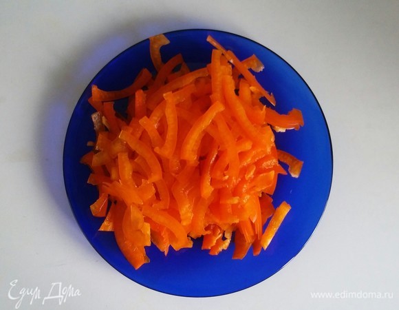 Перец разрезаем пополам и потом еще каждую половинку режем на три части, а после этого каждую часть перца режем тонкими поперечными полосками.