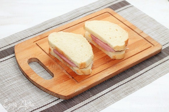 Накрыть бутерброды вторым куском хлеба, срезать лишние края.