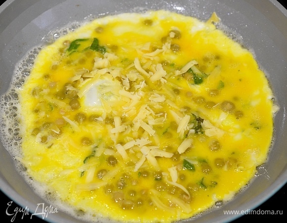 Когда омлет слегка схватится, посыпьте его тертым сыром.