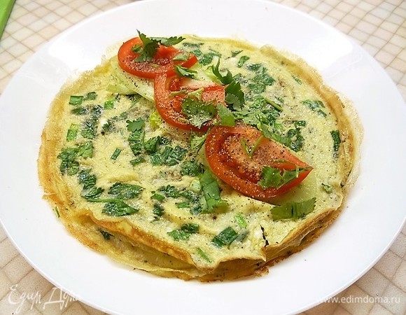 Готовые омлеты выкладываем на тарелки, сверху раскладываем нарезанный огурец, помидор и листья оставшейся петрушки, солим, перчим и сворачиваем рулетиками.