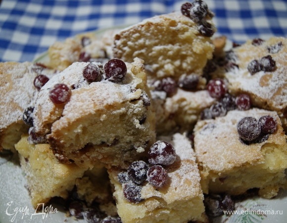 Даем пирогу остыть. Разрезаем его на квадратики. Посыпаем сахарной пудрой. Украшаем кусочки свежей клюквой.