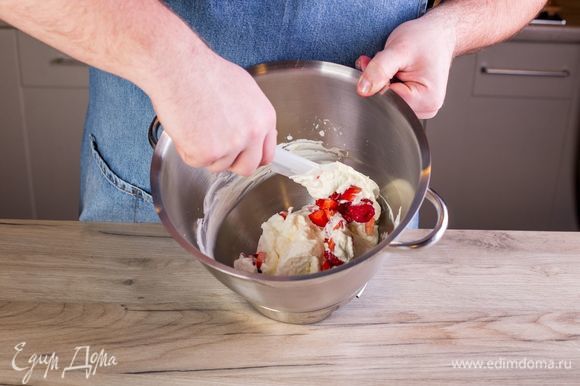 Добавьте ко взбитым сливкам ягоды и перемешайте силиконовой лопаткой.
