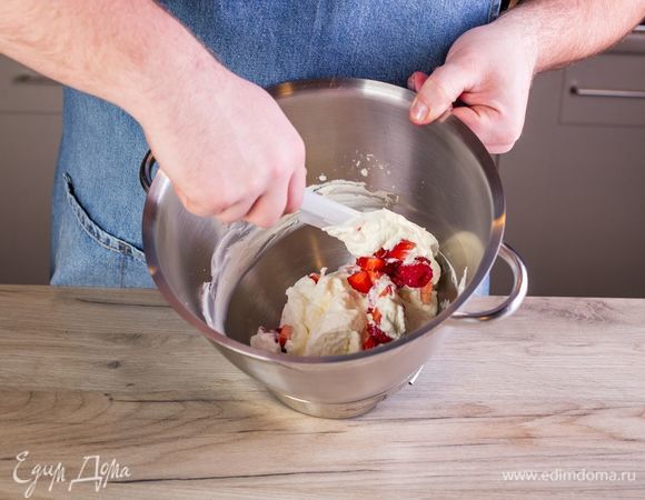 Добавьте ко взбитым сливкам ягоды и перемешайте силиконовой лопаткой.
