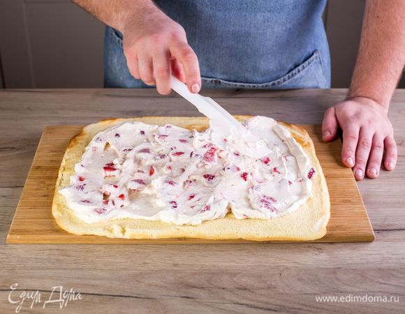 Снимите корж с противня, переверните и снимите бумагу. На готовый корж выложите сливки с ягодами ровным слоем.