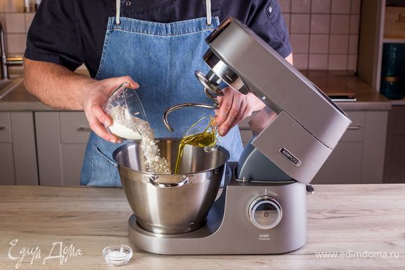 Всыпьте просеянную муку, соль и оливковое масло. При помощи насадки крюк замесите тесто и поставьте его прямо в чаше в теплое место на 30 минут, накрыв салфеткой или полотенцем.