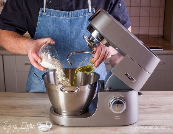 Всыпьте просеянную муку, соль и оливковое масло. При помощи насадки крюк замесите тесто и поставьте его прямо в чаше в теплое место на 30 минут, накрыв салфеткой или полотенцем.