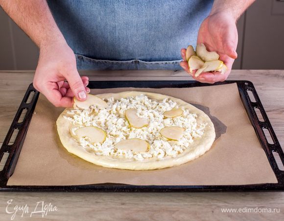 Выложите на тесто тертый сыр моцарелла, ломтики груши.