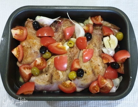Чеснок слегка раздавим, не снимая шелухи. Помидоры нарежем на четвертинки. Выкладываем к кролику чеснок, помидоры и оливки без косточек.