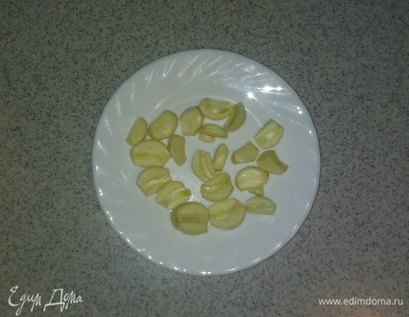 Очищенные зубчики чеснока разрезаем вдоль на две половинки.