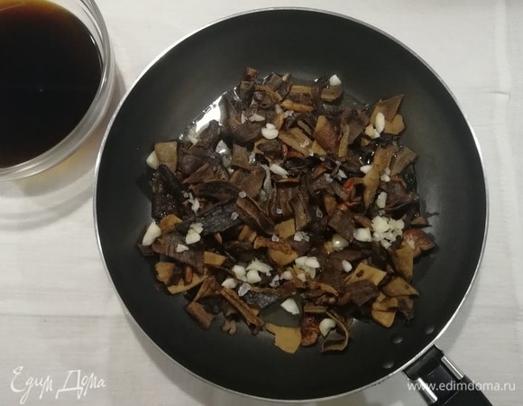 В сковороде разогреть 2 ст. л. оливкового масла, добавить чеснок, грибы, соль и перец. Жарить, помешивая, 1 минуту. Затем добавить процеженную через бумажное полотенце воду от грибов и тушить грибы на небольшом огне 20 минут.