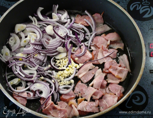 Приготовить соус. Для этого бекон нарезать и выложить в разогретую сковороду. Добавить лук с чесноком и обжарить до золотистого цвета.