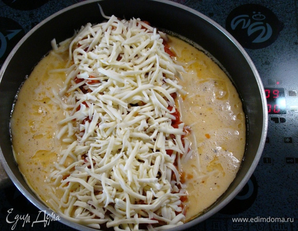 Сверху на соус выложить натертый сыр. Как только яичница схватится снизу, завернуть края к середине, накрыть крышкой и тушить минуты 3.
