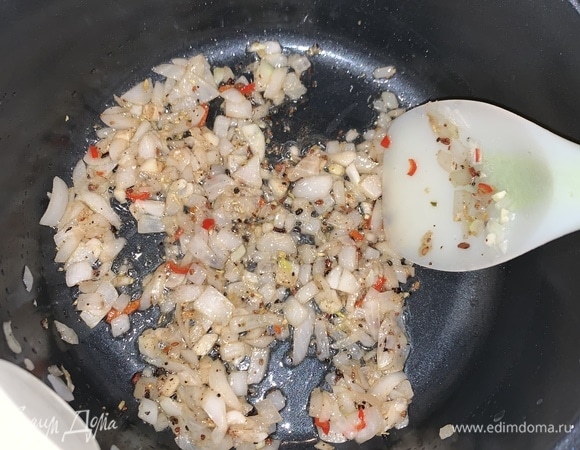 В тяжелой кастрюле разогреваем растительнок масло и обжариваем нарезанный лук и чеснок. Добавляем перец чили, корицу, гвоздику, кардамон и, помешивая, дожидаемся, когда лук станет золотистым.