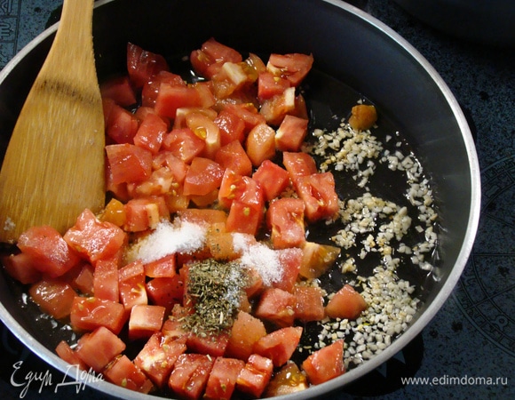 В разогретую сковороду влить 2 ст. л. оливкового масла и всыпать измельченный чеснок. Слегка подрумянить его. Затем к чесноку добавить нарезанную мякоть помидоров, всыпать соль, сахар и сушеный базилик. Все перемешать и потушить. По рецепту необходим свежий перец чили, но я не добавила его, чтобы блюдо не было острым.