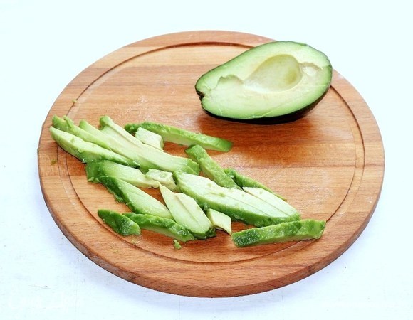 Авокадо очистить от кожуры, разрезать пополам и удалить косточку. Нарезать мякоть тонкими полосками.