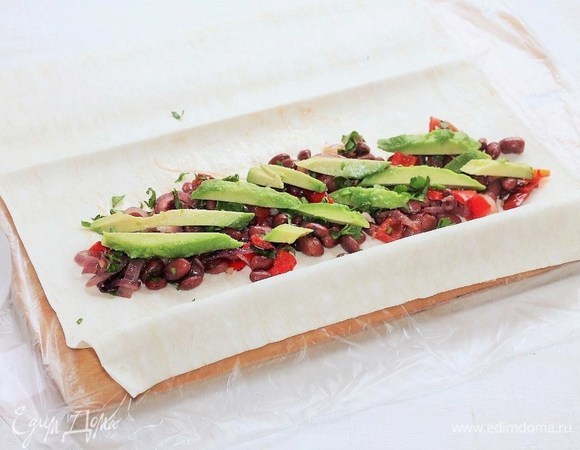 Тортилью (у меня тонкий лаваш) разрезать пополам, на каждую половину выложить начинку, посыпать кинзой, сверху поместить полоски авокадо и свернуть рулетами.