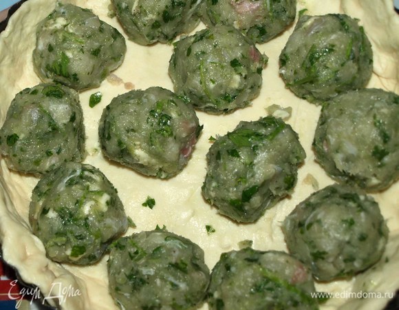 Форму для выпечки (20 см) смазать растительным маслом. Распределить тесто по форме, формируя бортики. Из подготовленного фарша делаем шарики и раскладываем. Посыпаем тертым пармезаном, рубленой зеленью петрушки.
