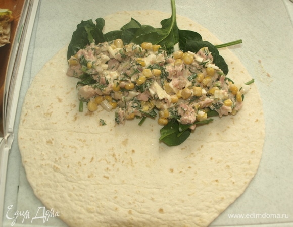 На край тортильи выкладываем шпинат. На шпинат выкладываем начинку из тунца. Заворачиваем тортилью рулетом.