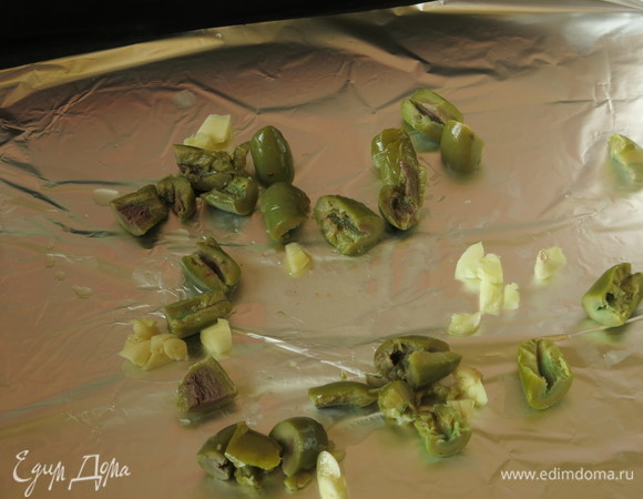 На противень кладем чеснок и оливки.