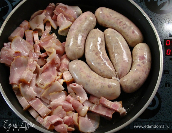 Растопить в глубокой сковороде сливочное масло и обжарить бекон и ветчину. Затем добавить колбаски и все обжарить до легкой золотистой корочки.