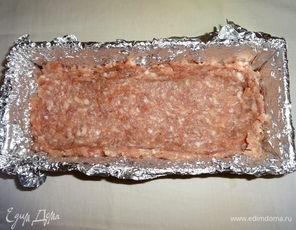 Выложить в форму половину фарша, сделать пальцами в фарше небольшое углубление.