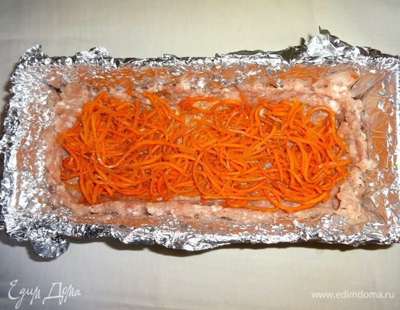 Морковь по-корейски отжать от маринада, выложить в углубление на фарш.