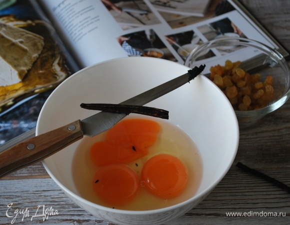 Изюм предварительно замочите в коньяке или роме. Стручок ванили разрежьте острым ножом и выньте семена. Два желтка и одно куриное яйцо поместите в глубокую чашку, чтобы было удобно все взбить в пышную массу.