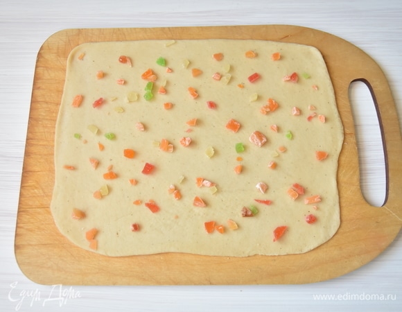 Отдохнувшее тесто раскатать как можно тоньше в пласт. Распределить по всей поверхности теста цукаты, которые предварительно нужно измельчить.